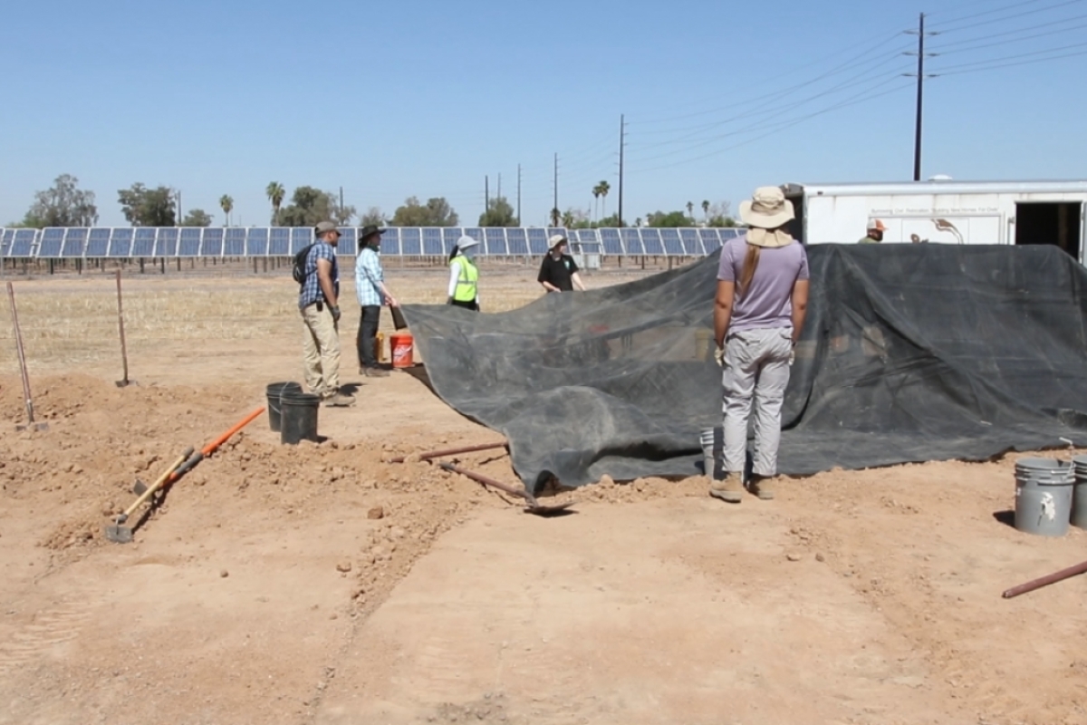 Volunteers stretch sturdy shade cloth over tent poles