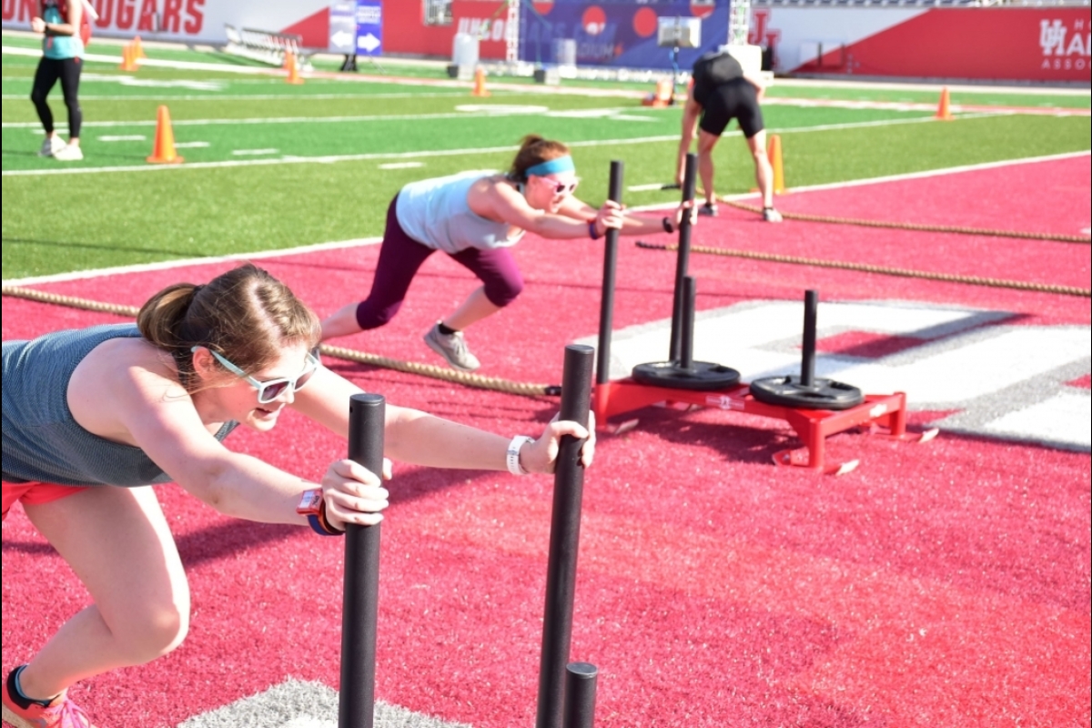 women pushing weights on a stadium's field