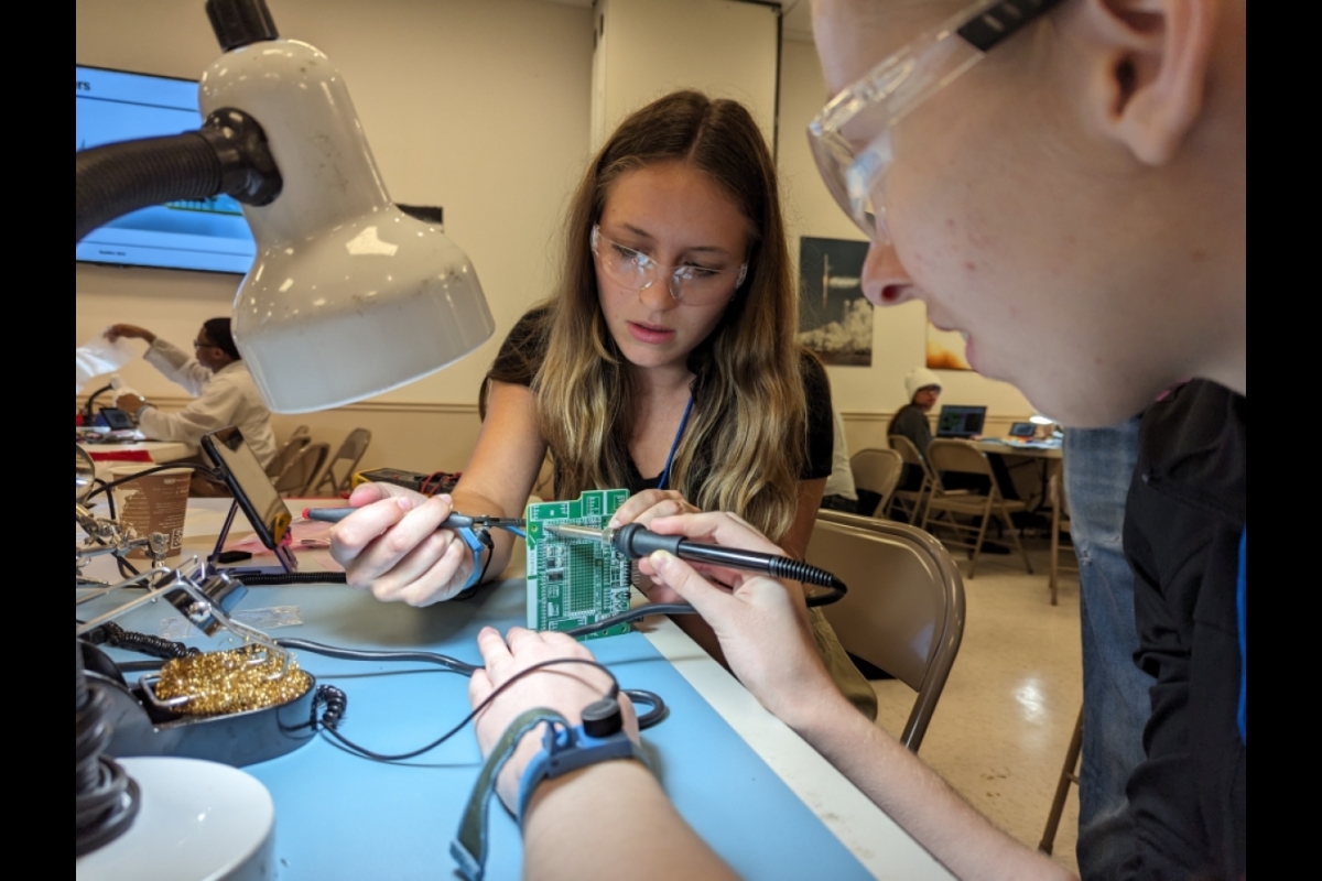 Two students soldering hardware.