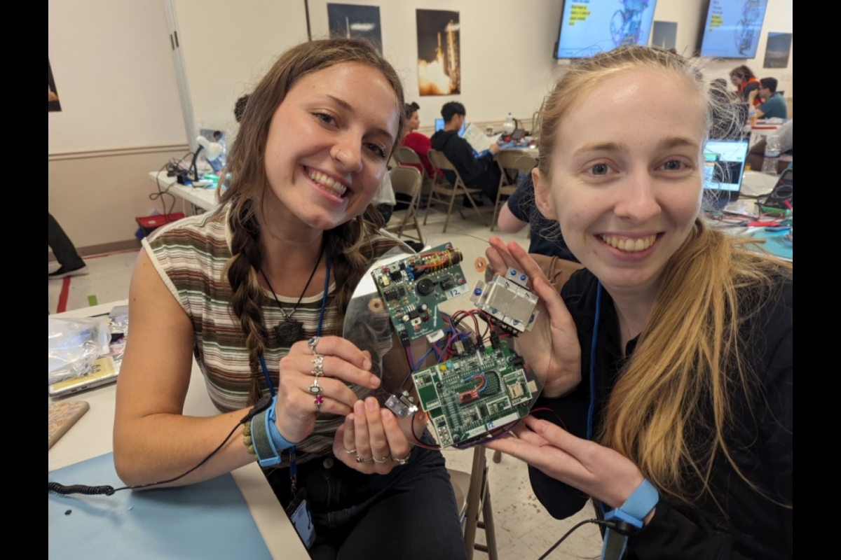 Two students holding a peice of hardware and smiling.
