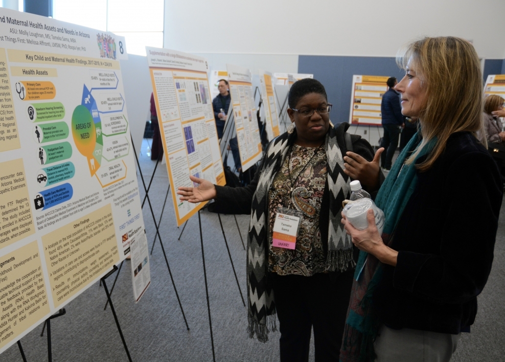 Tameka Sama shown talking in front of a poster-board presentation with Associate Professor Raminta Daniulaityte at the college's Faculty Research Day event at the Health Futures Center.