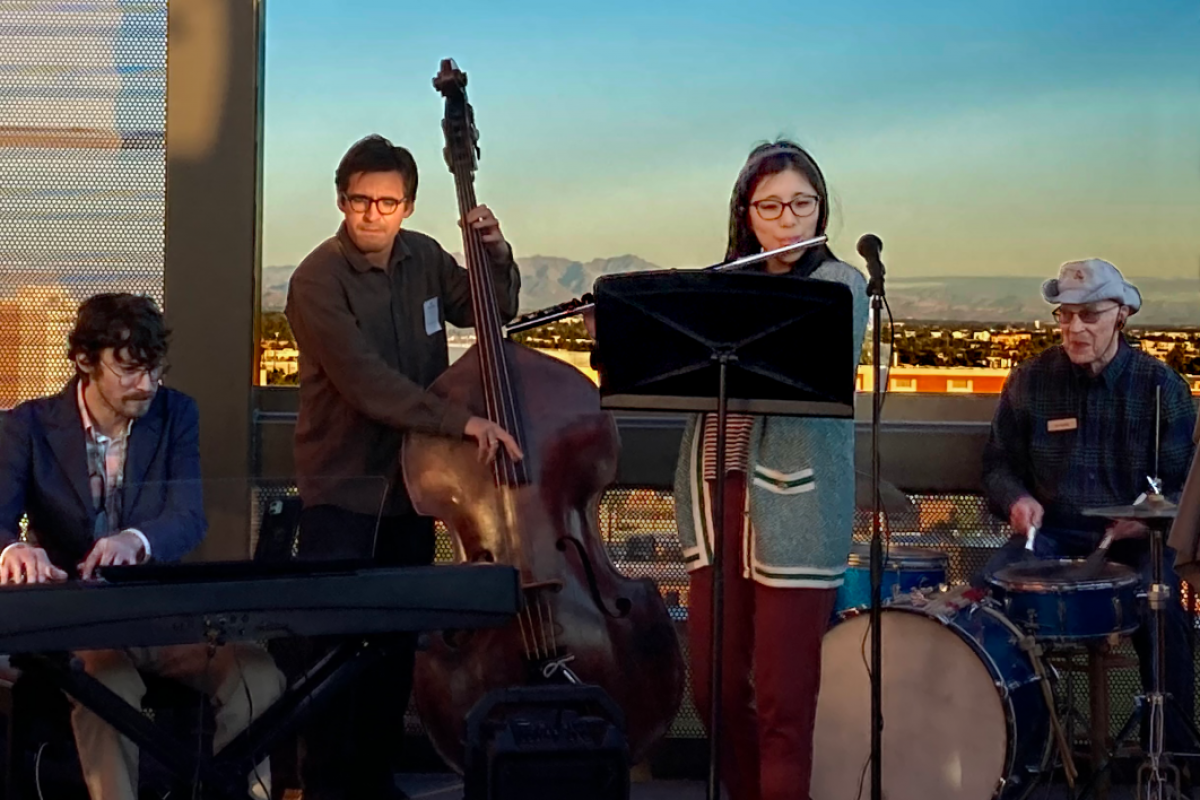 Students and a Mirabella resident in the middle of a musical performance on a rooftop.