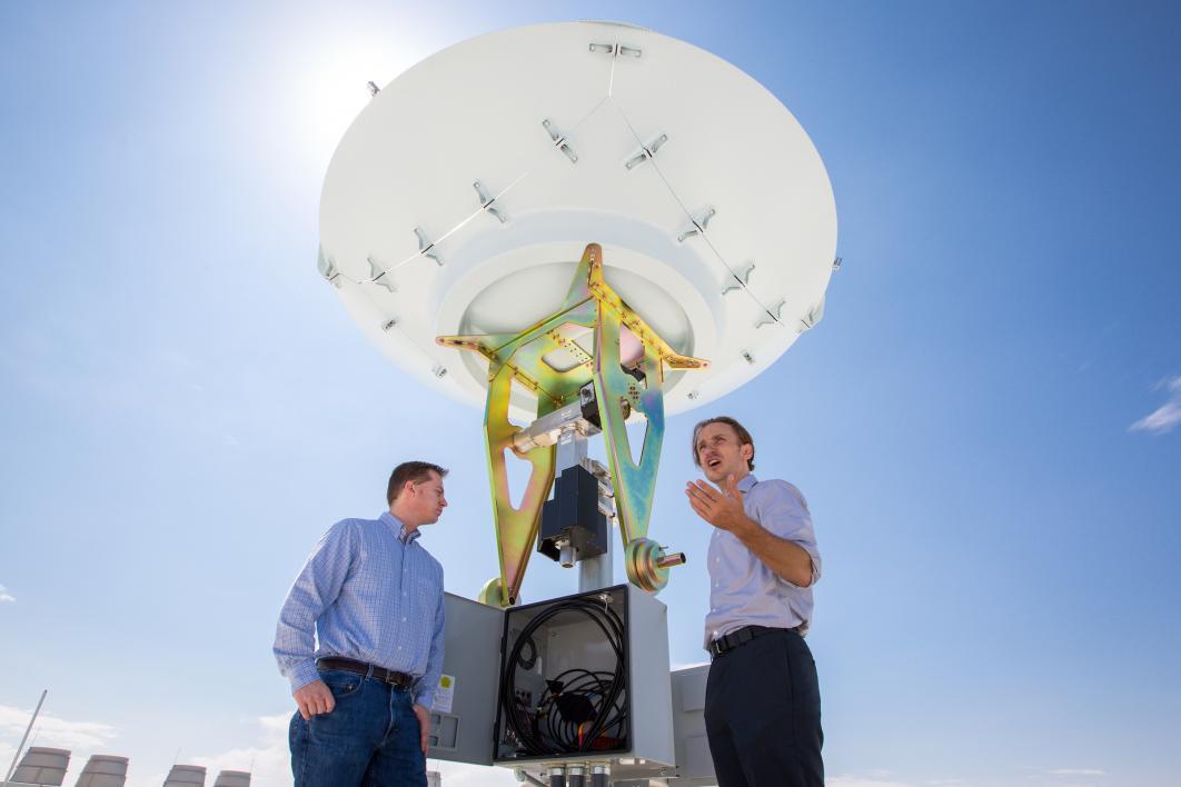 two men talking by satellite dish