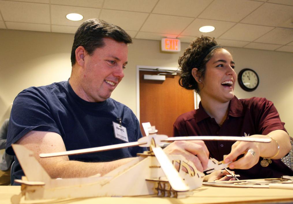ASU recreation therapy student laughs while assisting veteran client assemble a laser-cut wooden helicopter