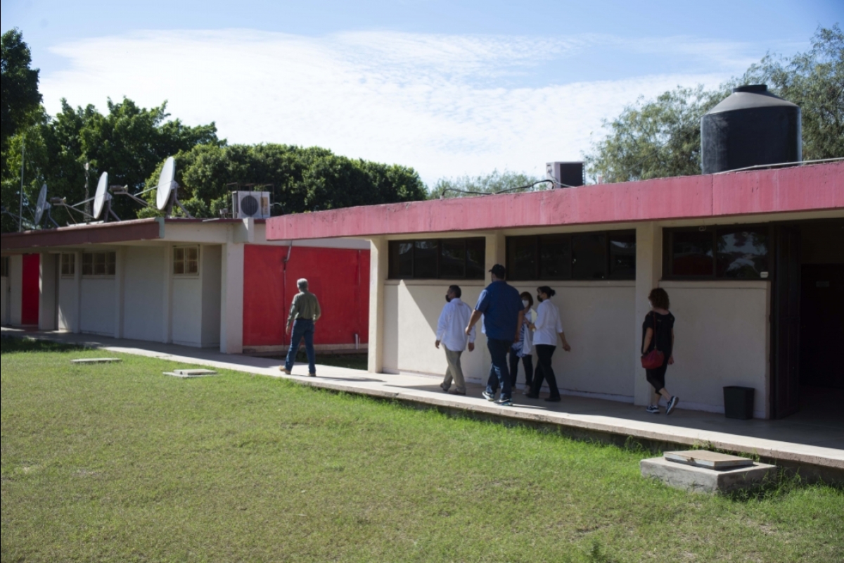 People walking along the exterior of a school, assessing its fitness as a site for a free health care clinic.
