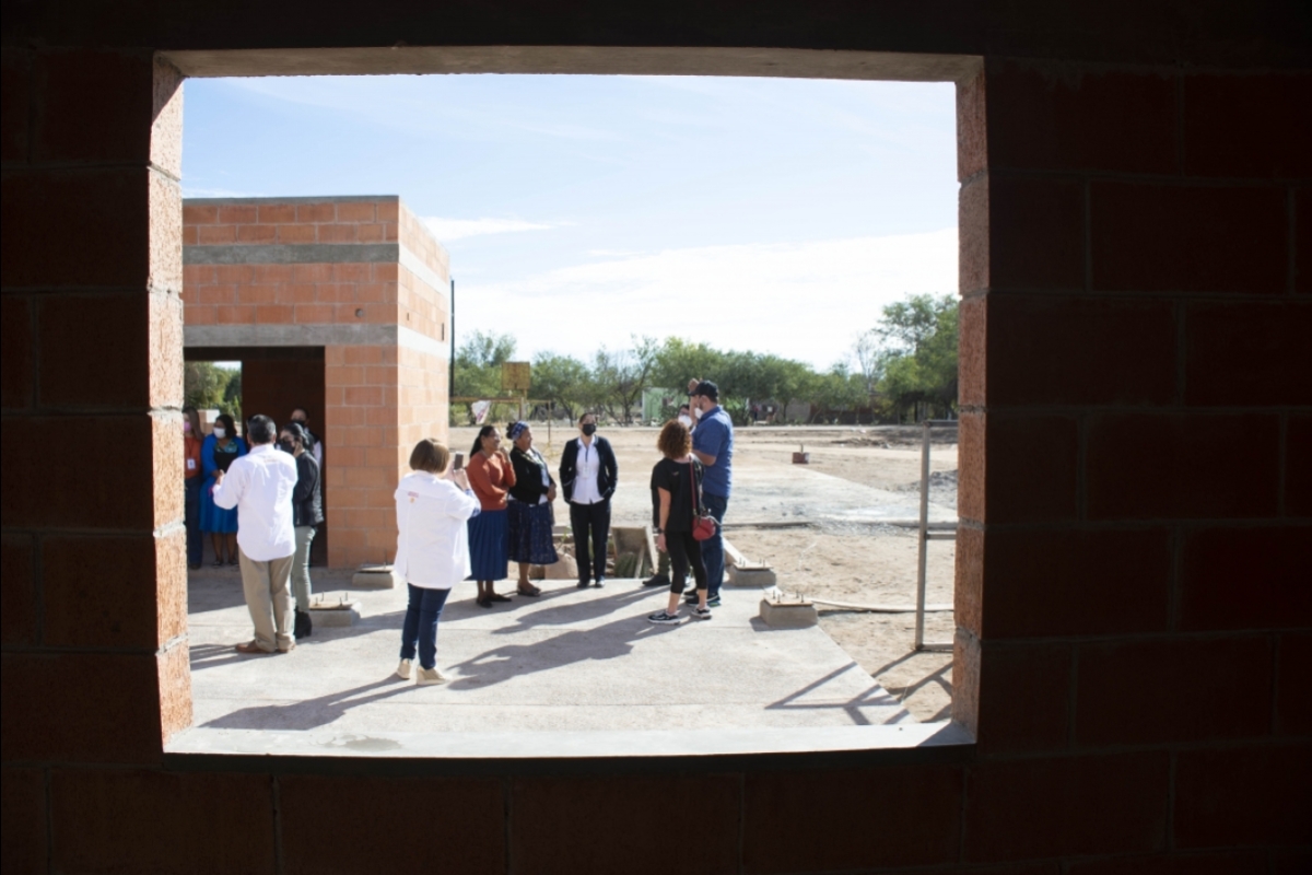 A group of people gathered outside of a health clinic under construction.