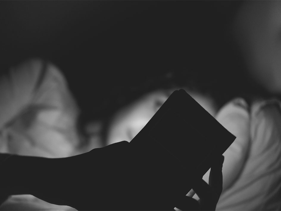 woman lying down in bed using phone