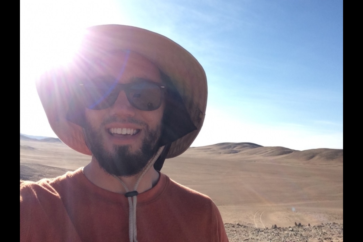 Selfie of ASU graduate student Donny Glaser in the Atacama Desert wearing a wide-brimmed hat and sunglasses with the sun shining behind him.