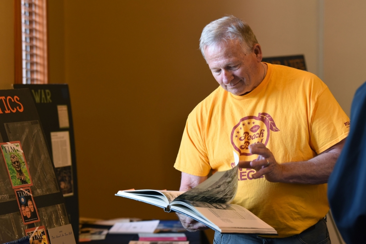 A man in an ASU T-shirt looks through a yearbook
