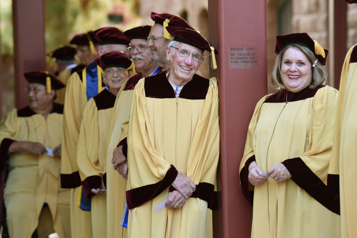People in gold graduation gowns wait in a line