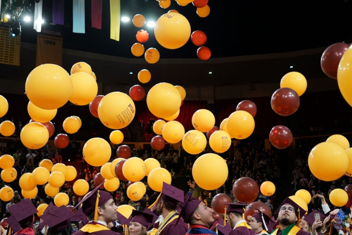 Maroon and gold balloons falling from the ceiling of an arena.
