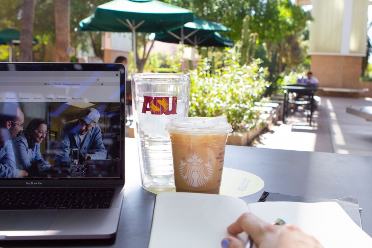 From the point of view of a person sitting at a table with a laptop, notebook and several drinks
