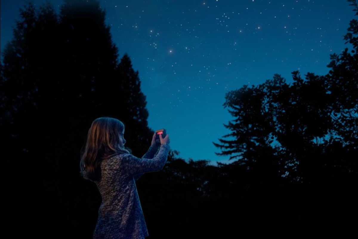 young girl holding up a device to collect data from the night sky