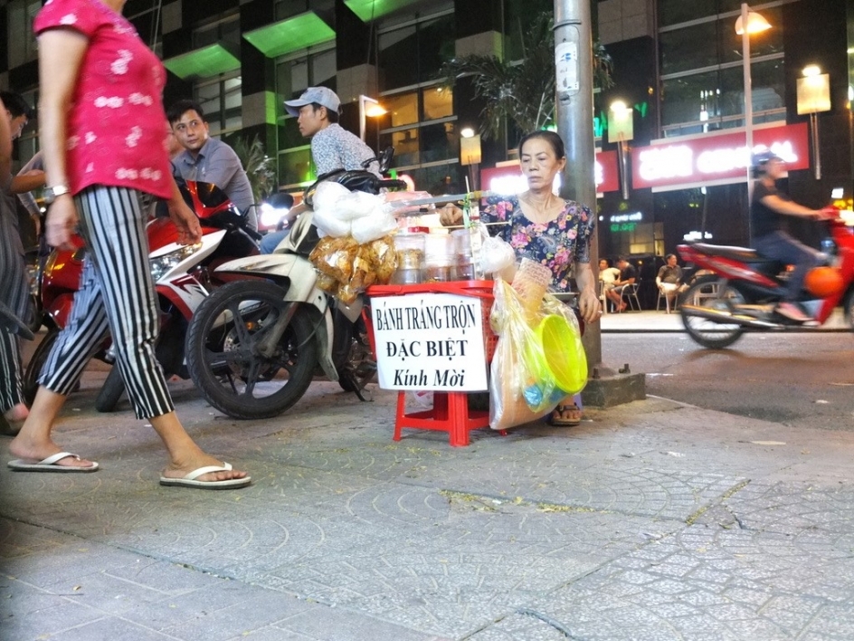 A street vendor sells wares as people pass by in Ho Chi Minh City.