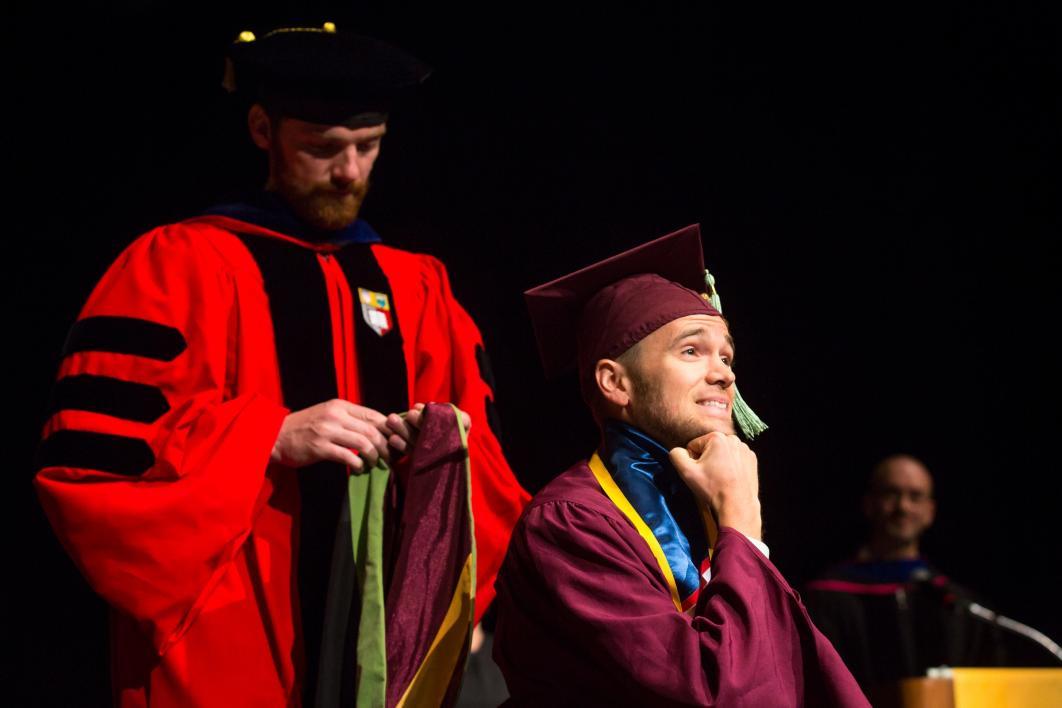 graduate putting resting his chin on his fist before being hooded
