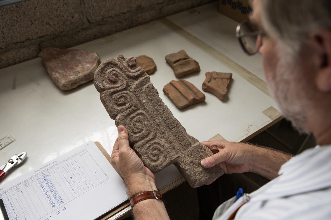 The lab director looks at an ancient object at the Teotihuacan Research Laboratory