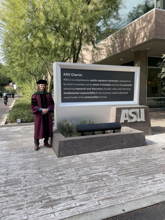 man standing next to ASU charter sign