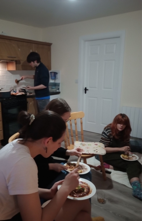 A group of people gathered in an apartment eating food.