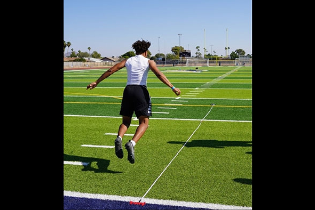 High school athlete jumping on a football field.