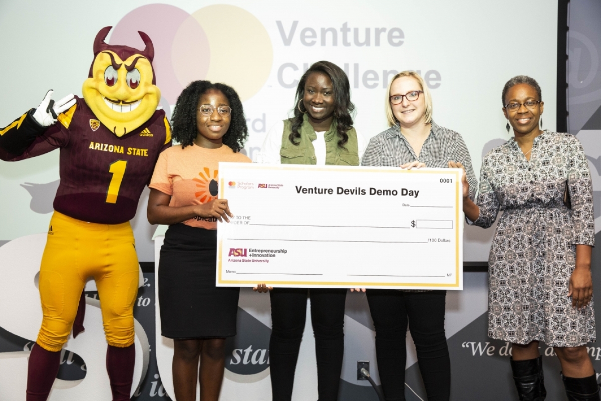 Winning venture presenter receives check with Sparky
