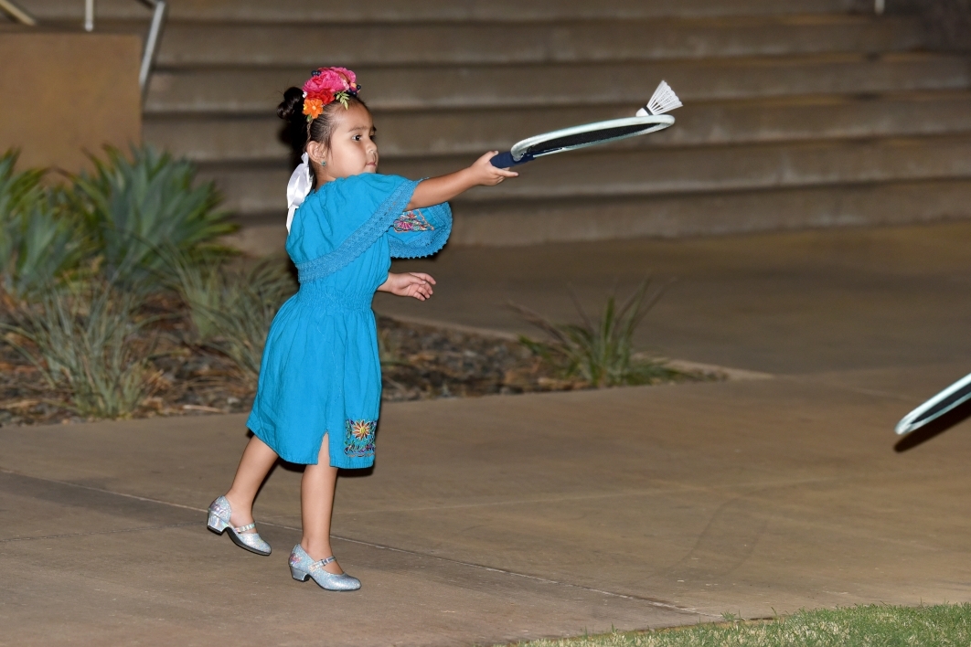 Small girl in a bright blue dress playing badminton.