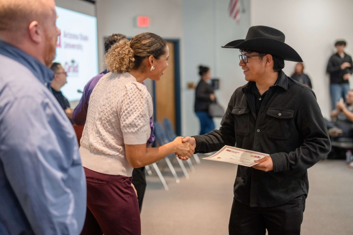 Student shaking a teacher's hand as he accepts a certificate.