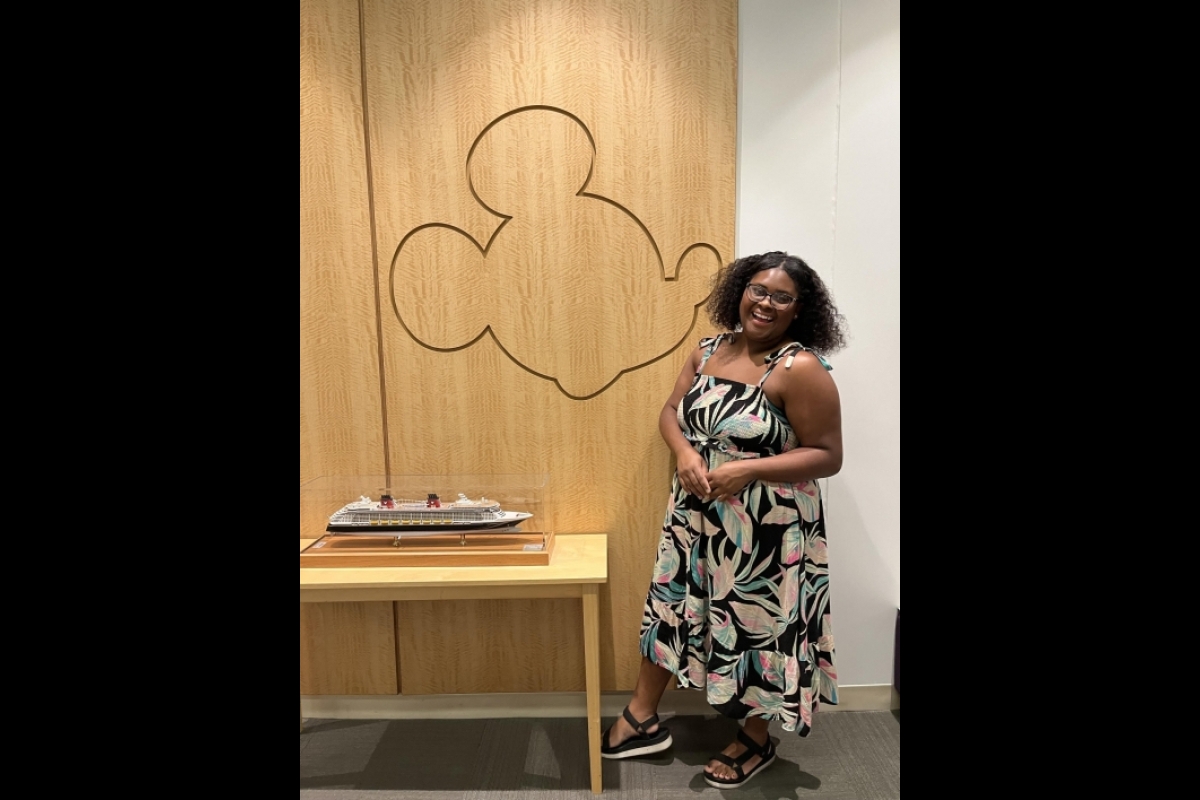 Smiling woman standing in front of a wall with an outline of Mickey Mouse.