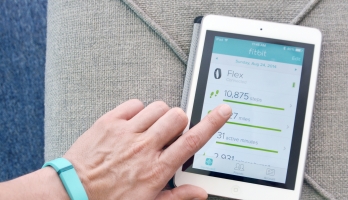 Hand hovering over a tablet displaying physical activity data.