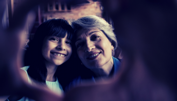 A young girl and her grandma smile at the camera