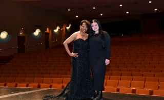 Women dressed in black pose in front of an empty theater.