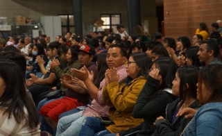 Group of people seated in an audience, clapping.