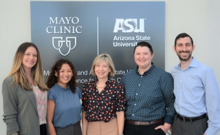Group of people pose for a photo in front of a sign with Mayo Clinic and Arizona State University logos.