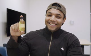 ASU College of Integrative Sciences and Arts alumnus Jordan Collins holds up a small jar of okra-seed oil.