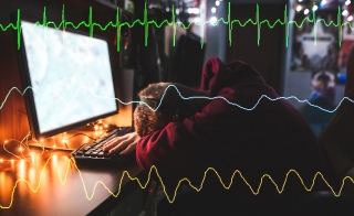 Gamer with head down in front of desktop overlaid with heart monitor line graphs