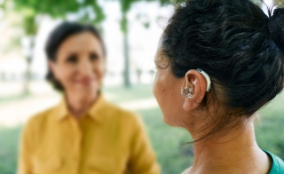 Woman wearing a hearing aid while talking to her friend