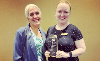 Katherine O'Flaherty, Honors Faculty Fellow in Barrett, The Honors College at ASU, standing next to another woman while smiling and holding an award.