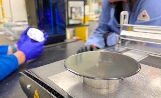 A wafer of semiconductor material sits on a table in a laboratory setting.