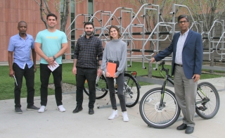 Professor Ram Pendyala's transportation research team and himself posing near a bike rack on campus.
