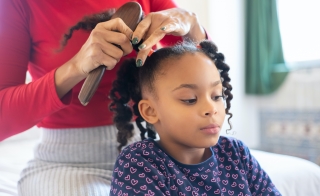 woman brushing the natural hair of her child