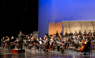 Wind band students performing on a stage.