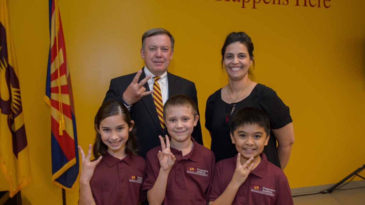 ASU President Michael Crow posing with parent and students of ASU Prep Academy