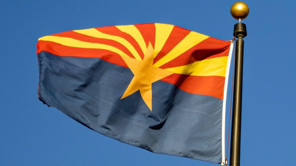 The Arizona flag flying against a blue sky background.