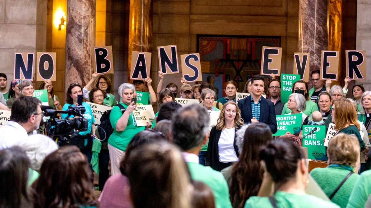 Large group of people at a protest with signs that read "No Bans Ever."