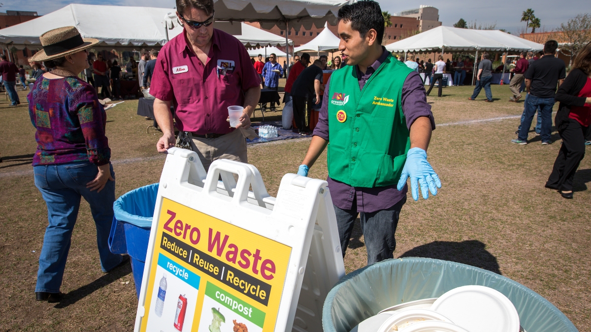 two people in front of waste bins