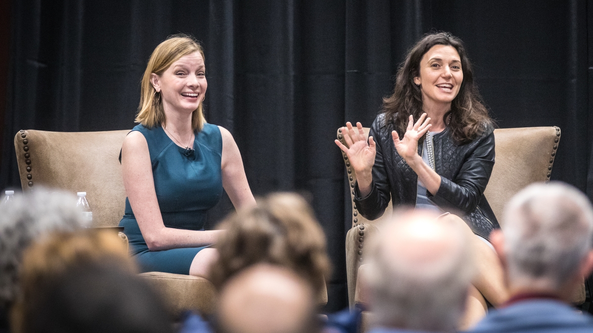 The Pollsters podcast hosts Kristen Soltis Anderson and Margie Omero speak on stage at an event