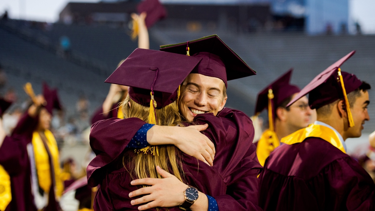 two grads giving each other a hug