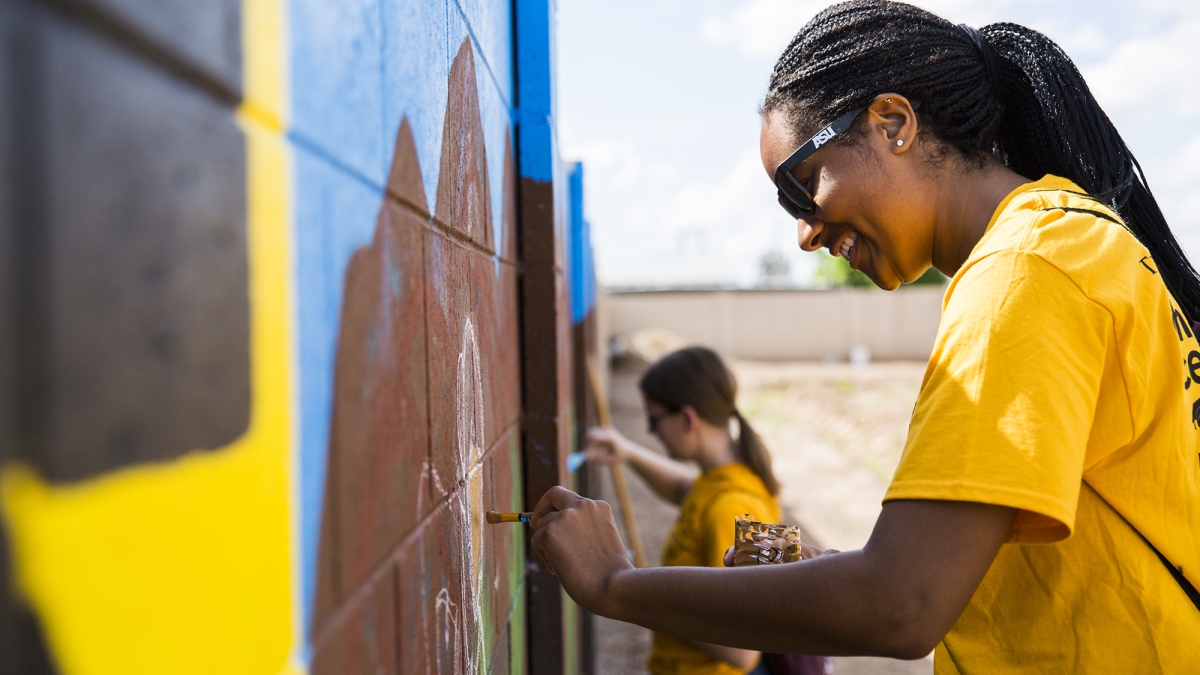Students paint a mural during the Devils in Disguise day of service.