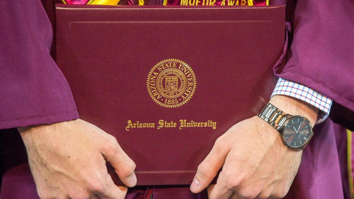 A new graduate holds his diploma