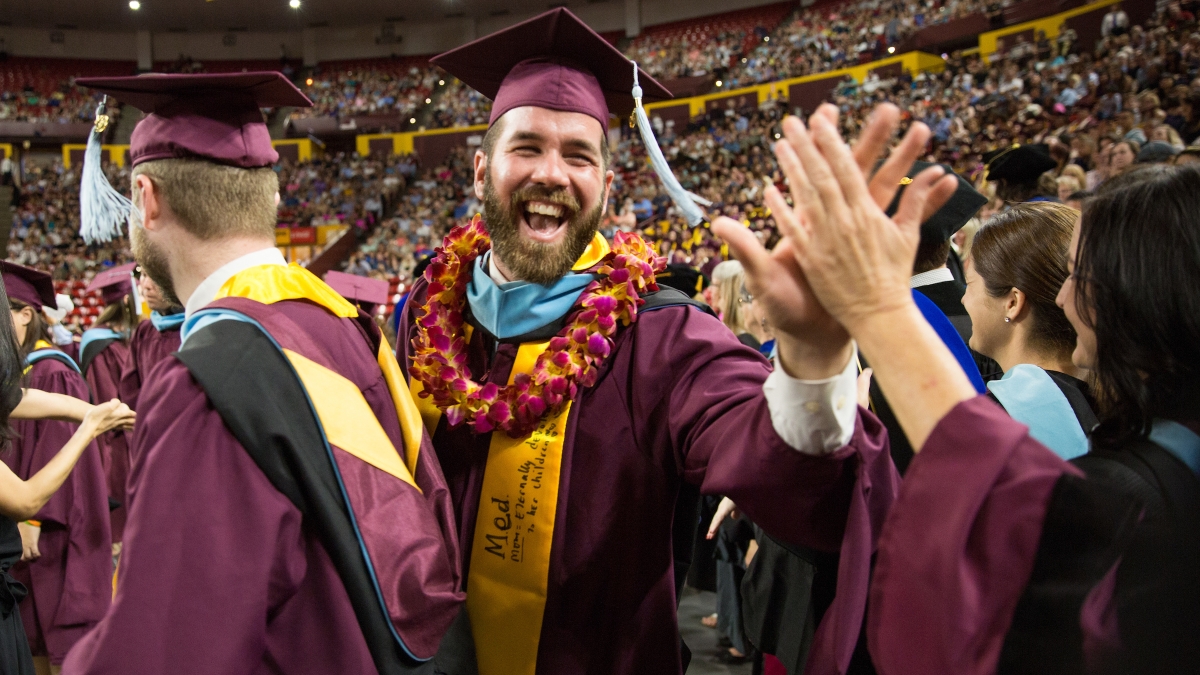 ASU master's student Collin Perryman receives high fives from professors on his way to receive his diploma during the Mary Lou Fulton Teachers College Convocation.