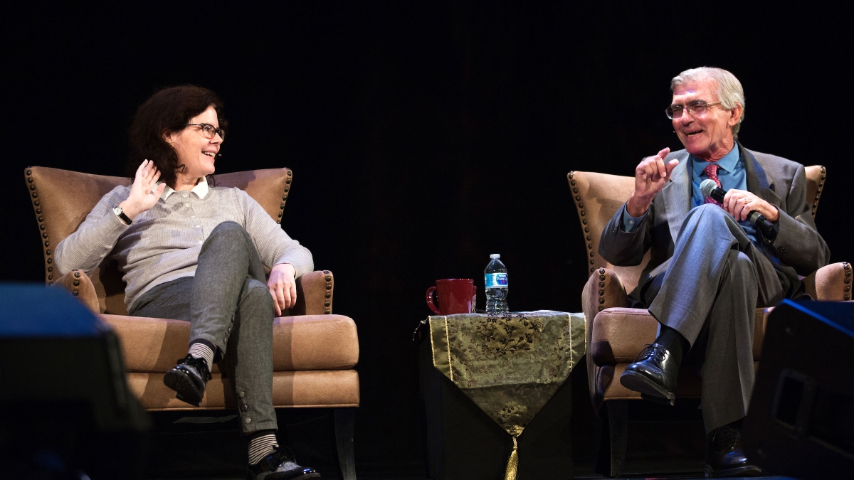 A man and a woman participate in a Hamilton panel onstage
